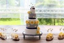 Sweet table geel grijs met grote bruidstaart en cupcakes met toef van creme en eetbare hartjes lollie